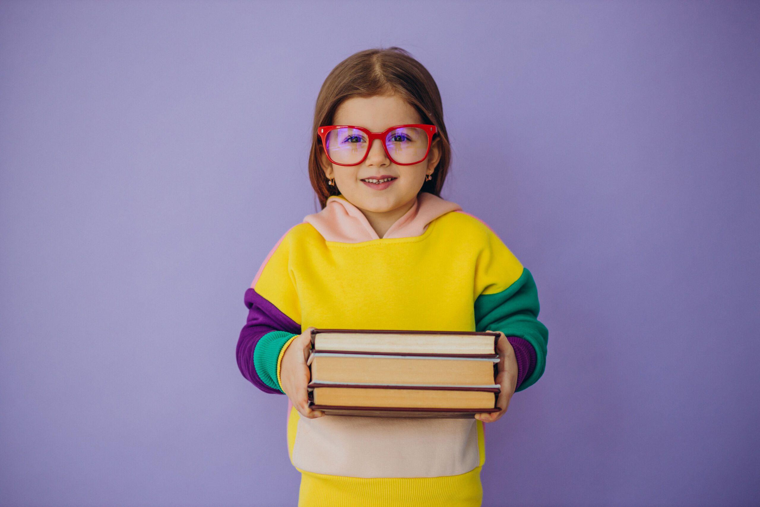 Cute little school girl holding books isolated in studio